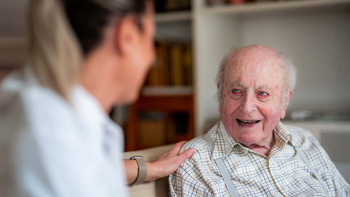 Pflegefachkraft betreut pflegebedürftigen Mann zu Hause